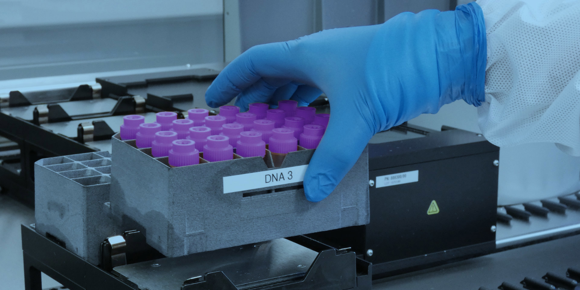 a tray of samples marked dna 3 held by someone in ppe